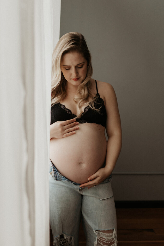 pregnant woman cradles her stomach, looking down at her stomach