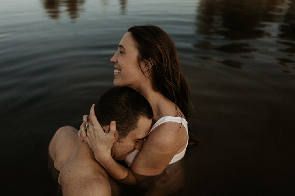 woman and man hold each other in water and smile
