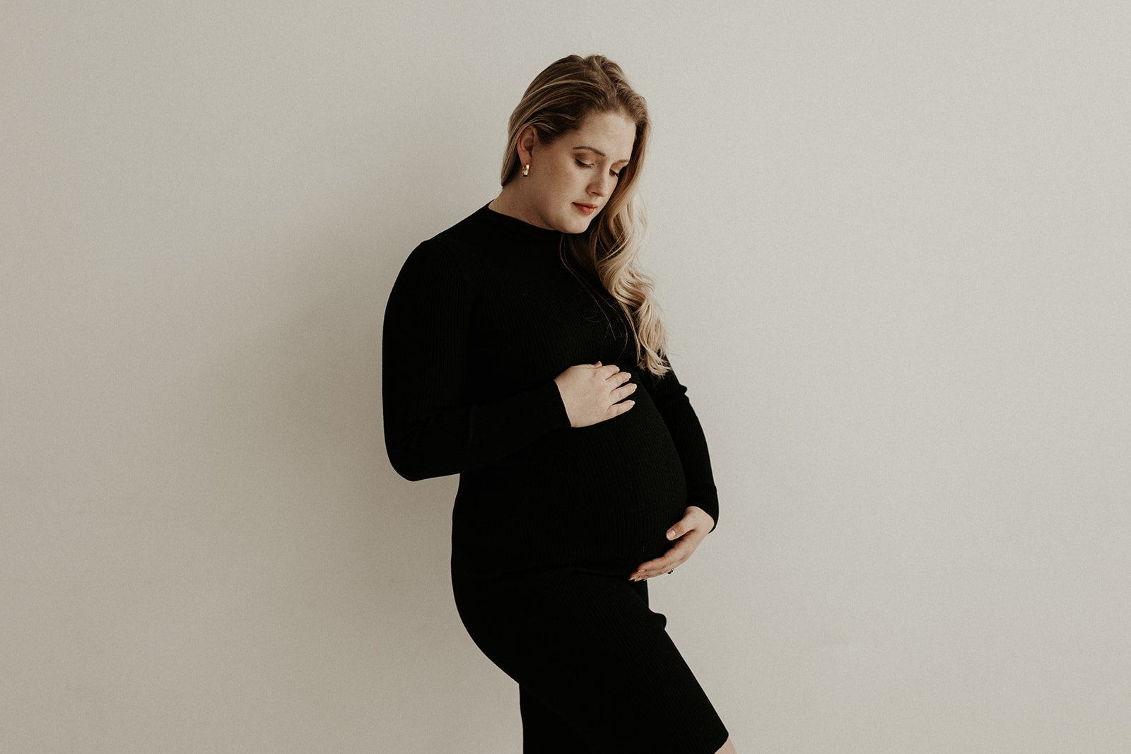 white pregnant woman wearing black holds stomach