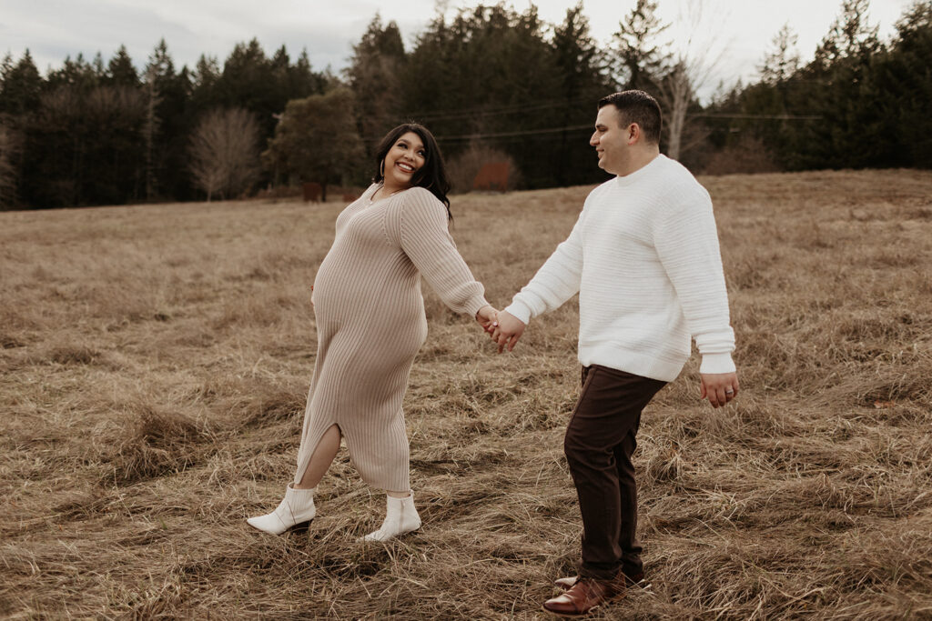 couple walks in brown field during gig harbor maternity session