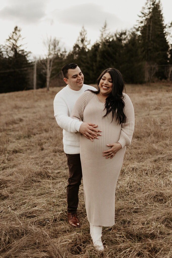 couple cuddles in brown field during gig harbor maternity session