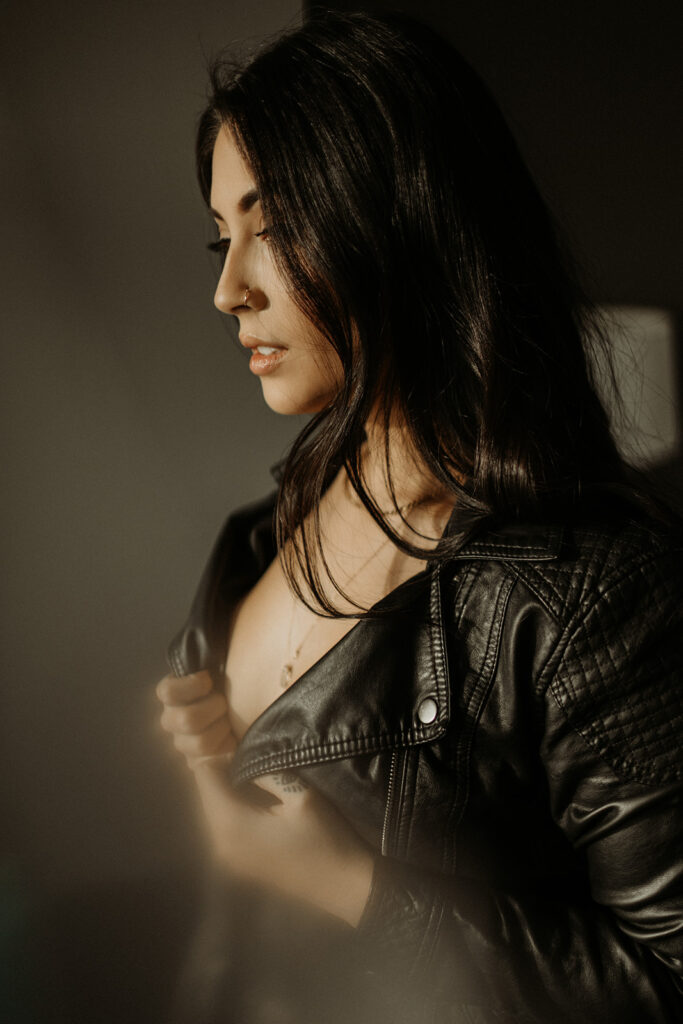 girl in black leather jacket poses during boudoir shoot