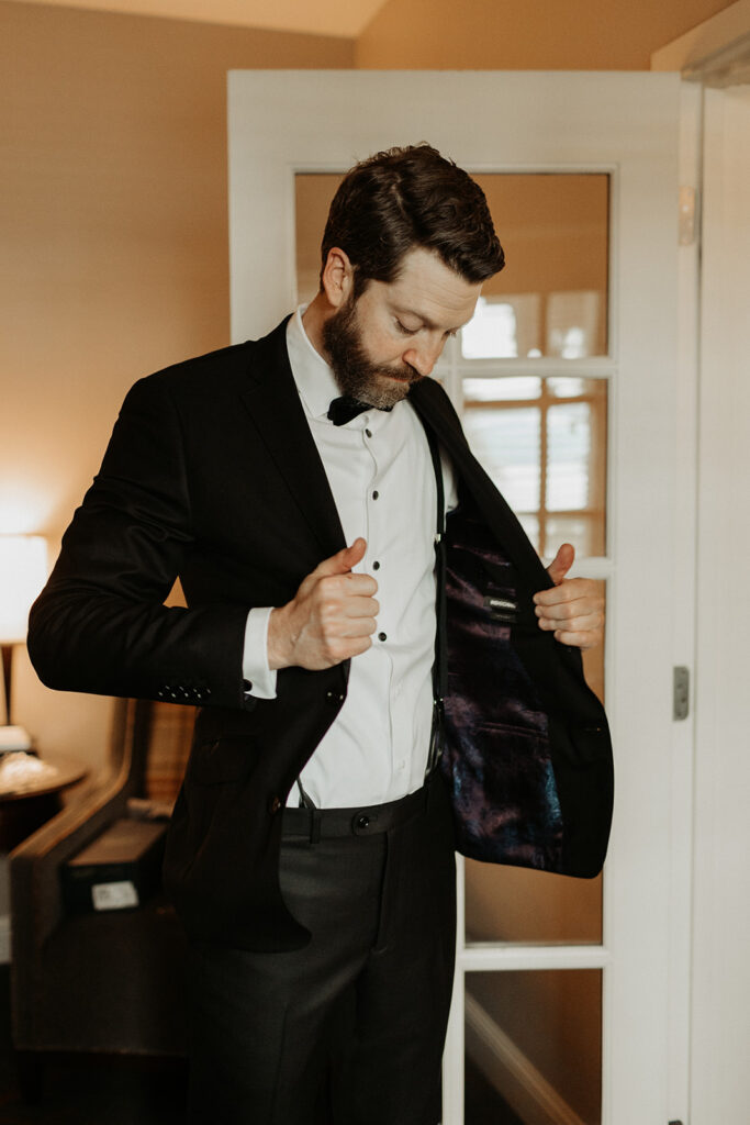 groom in black suit buttons jacket