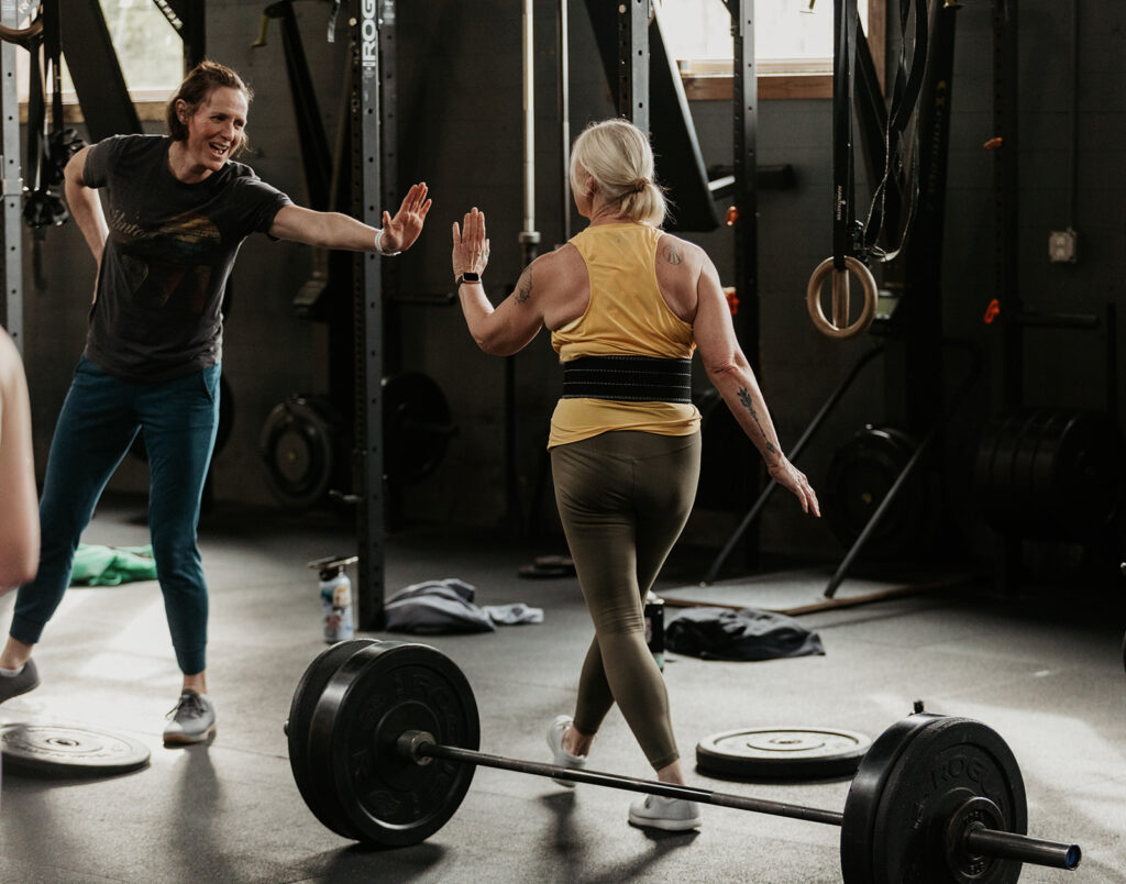 two women high fiving in a gym