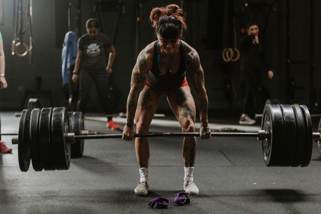 woman picks up a barbell with lots of weight on it