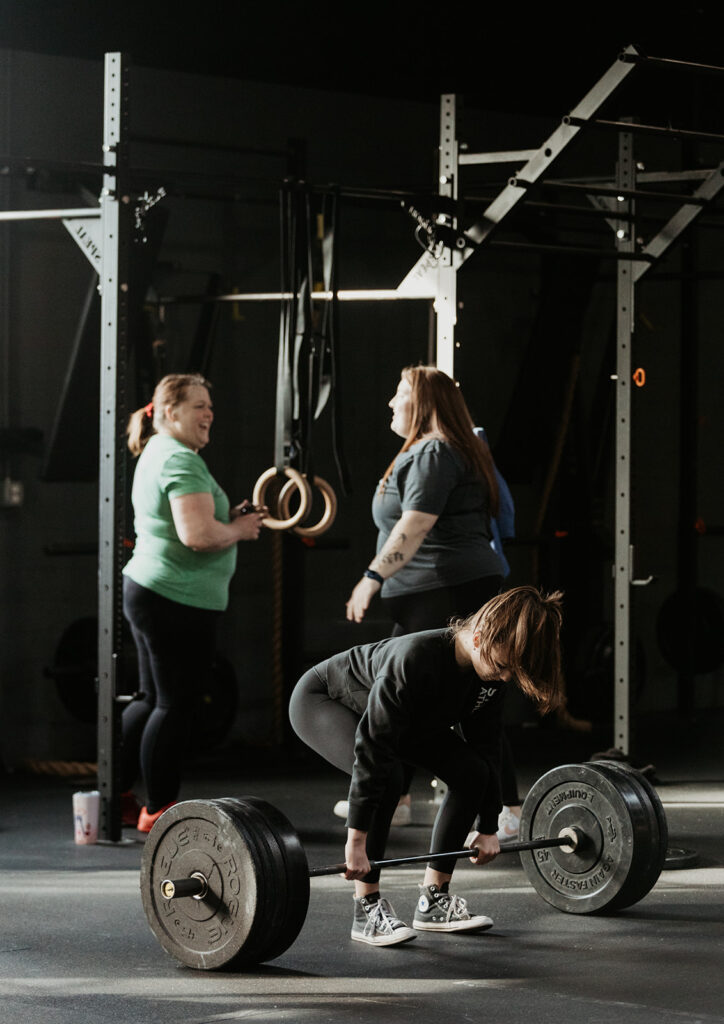 woman leans over to pick up barbell